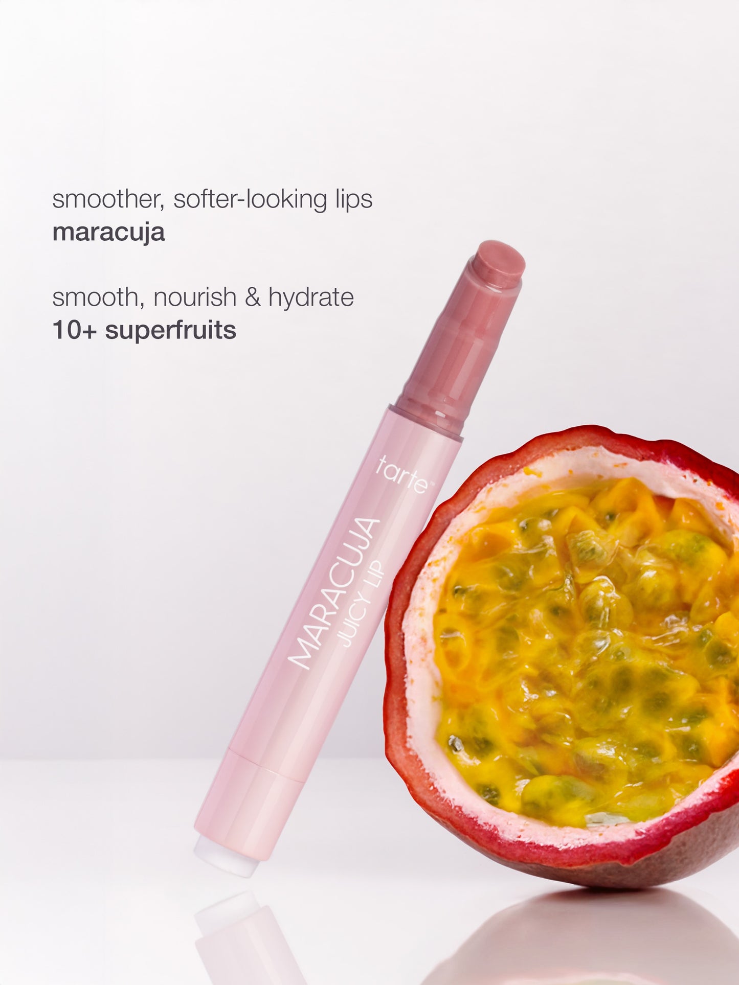 A lip gloss tube leans against a halved passion fruit on a white surface. Text reads: smoother, softer-looking lips maracuja smooth, nourish & hydrate TIA superfruits.