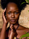 Woman with natural hair and makeup, with text '16-hr wear tina in espresso' on a blurred background wearing tarte CC serum 
