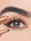 Close-up of an eye with a brown eyeliner pencil being applied.
