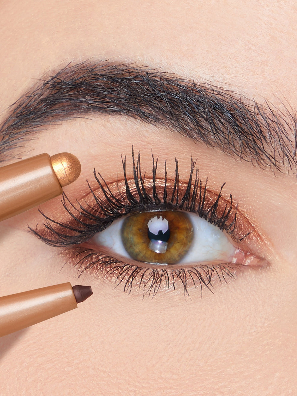 Close-up of an eye with a brown eyeliner pencil being applied.