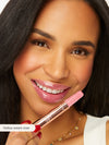 Woman holding a pink lipstick with a close-up of her face.