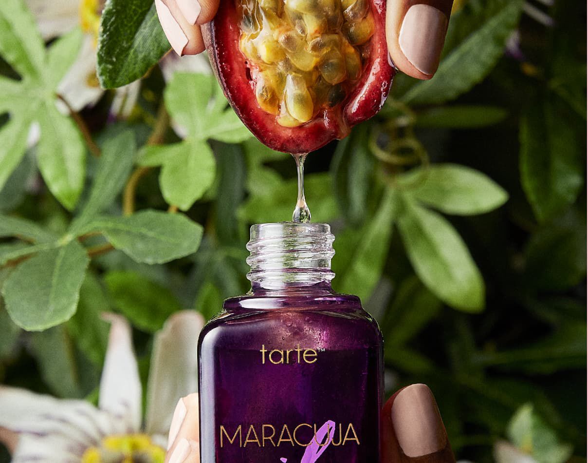 hand squeezing maracuja into the tarte maracuja oil bottle